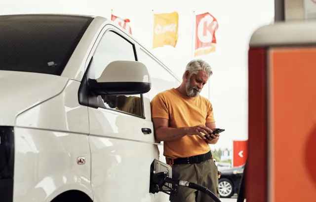 Man exploring Circle K's app on his mobile phone, while fueling his van at a Circle K station